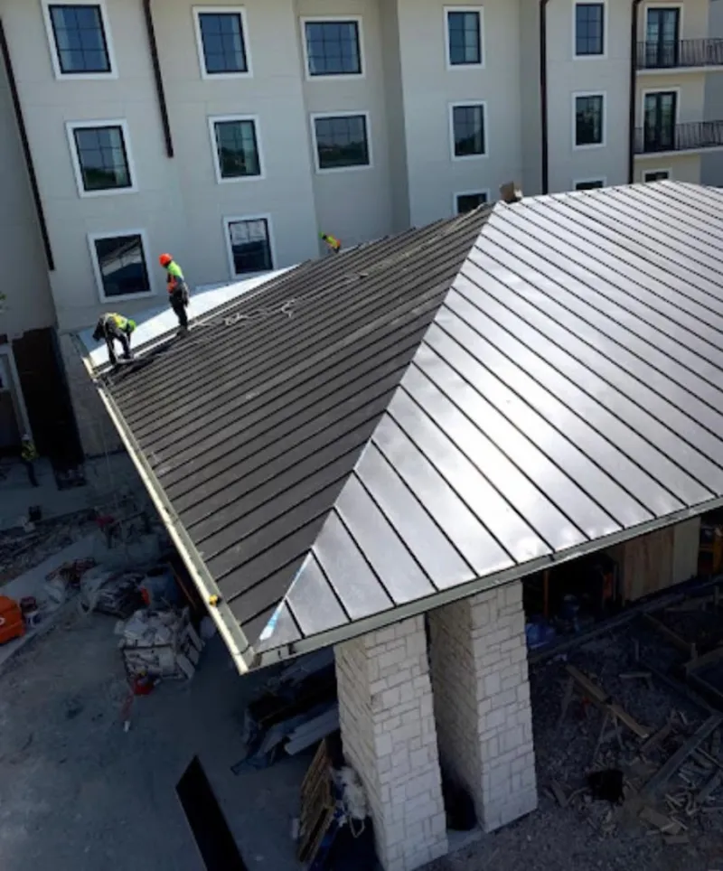 Crew installing standing seam metal roof panels on a commercial project in New London